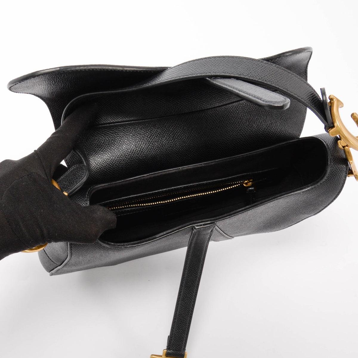 Everyday essentials arranged beside and inside a Dior Saddle Bag.