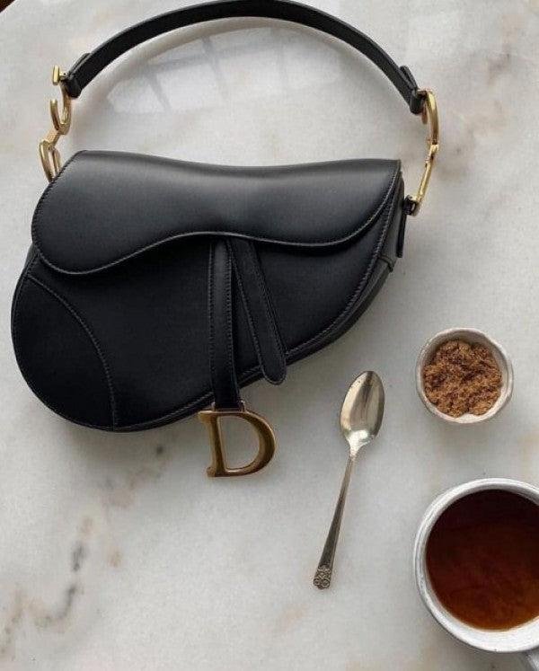 Dior Saddle Bag photographed with a clear view of its curved profile.