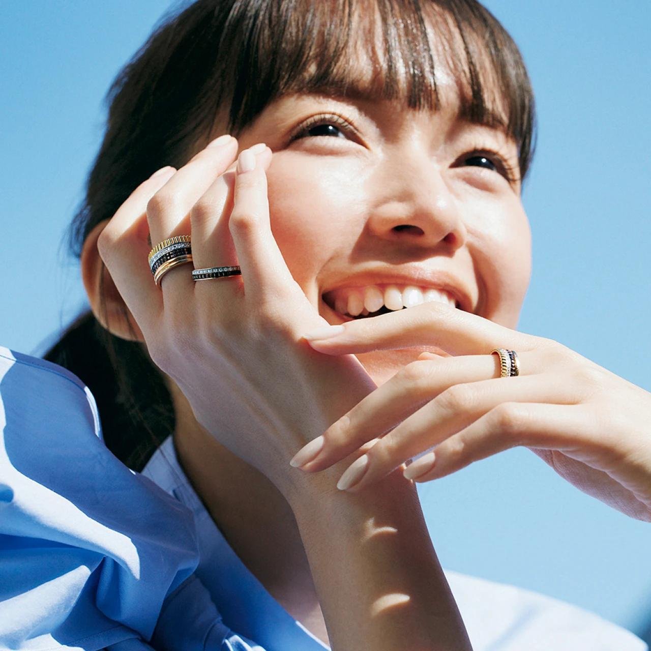 Boucheron Quatre rings worn on both hands against a blue background.