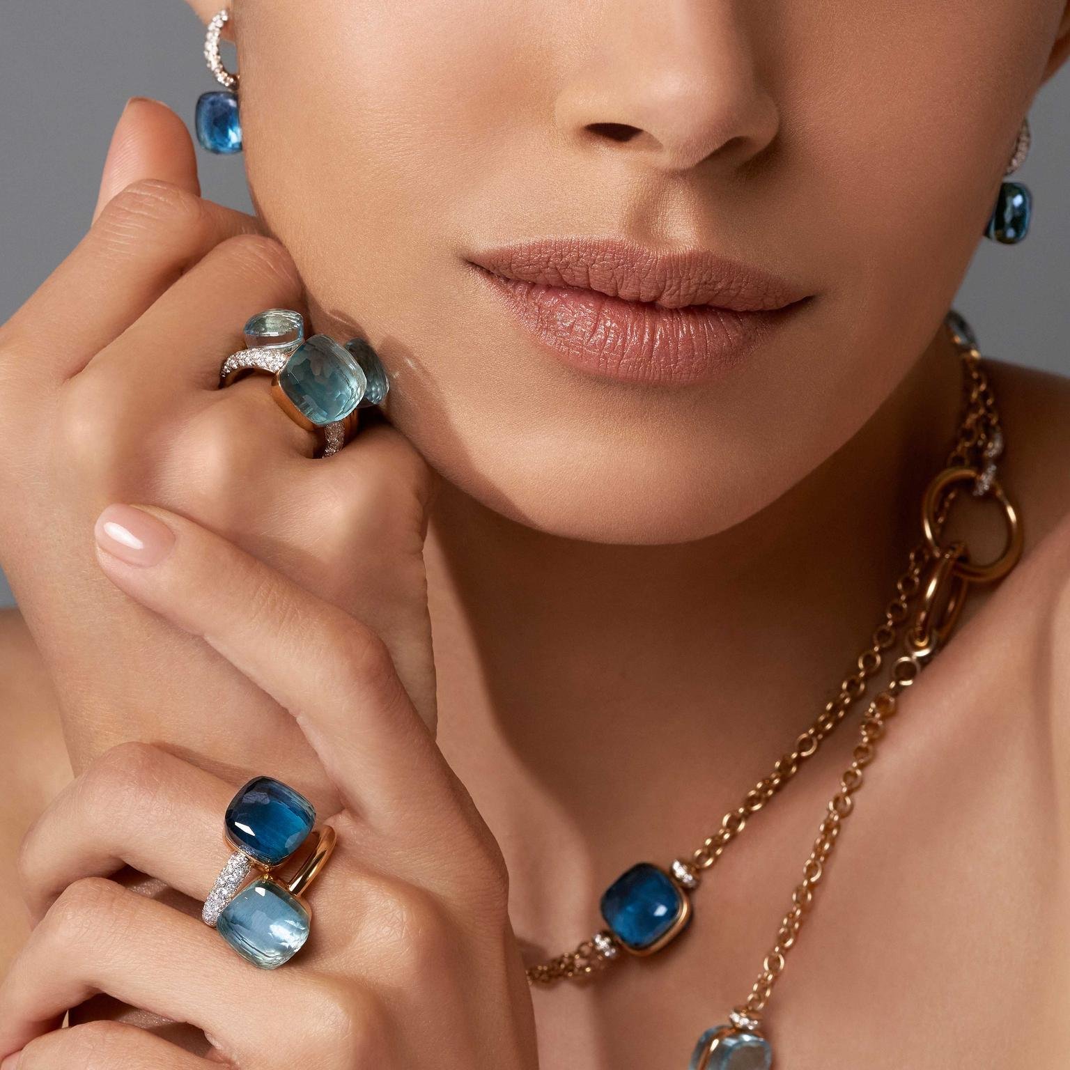 Model wearing multiple blue Pomellato Nudo rings and matching jewellery.