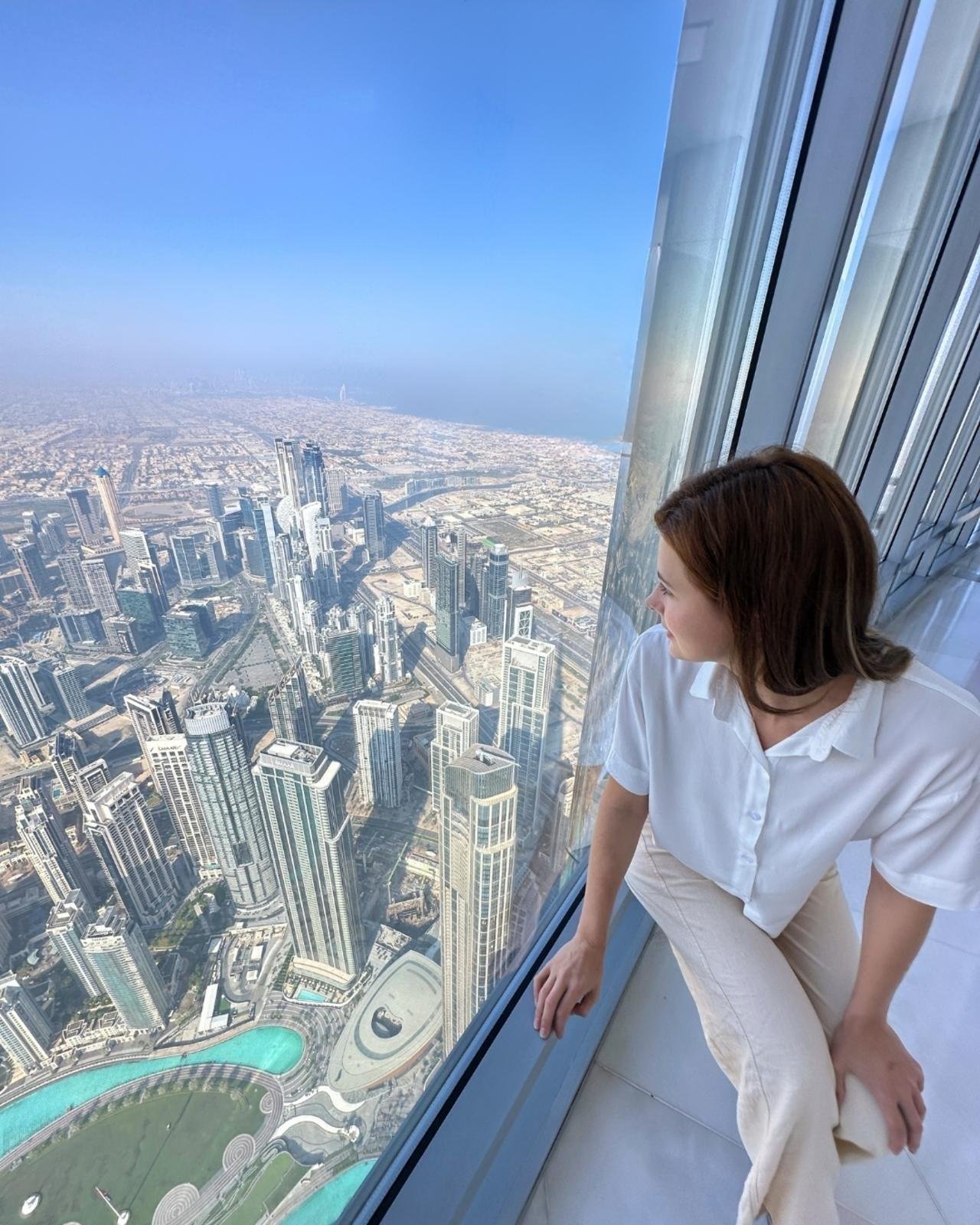 Visitor photographing the view through Burj Khalifa observation deck windows.