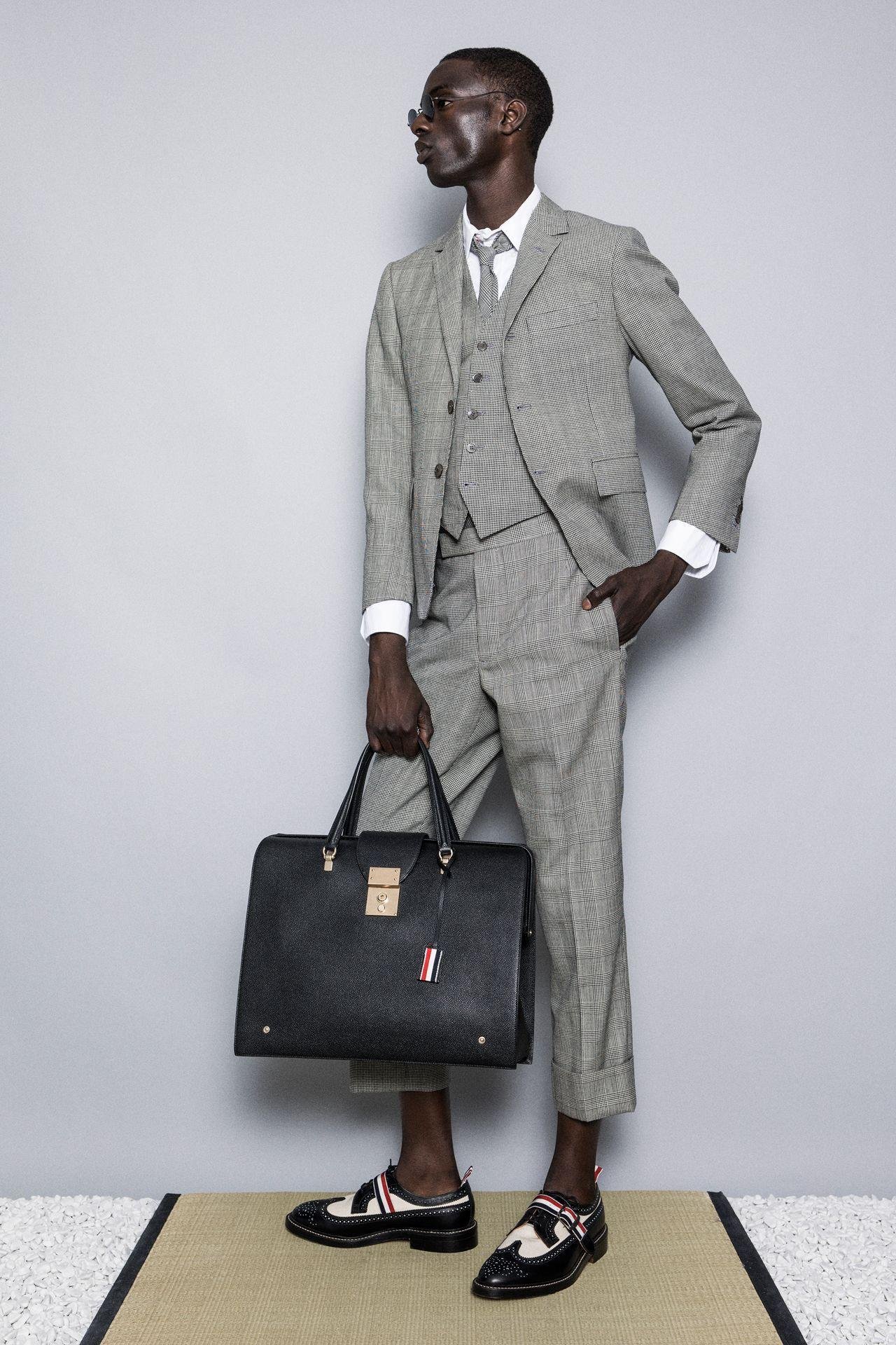 Model wearing a grey Thom Browne suit with cropped trousers and black shoes.