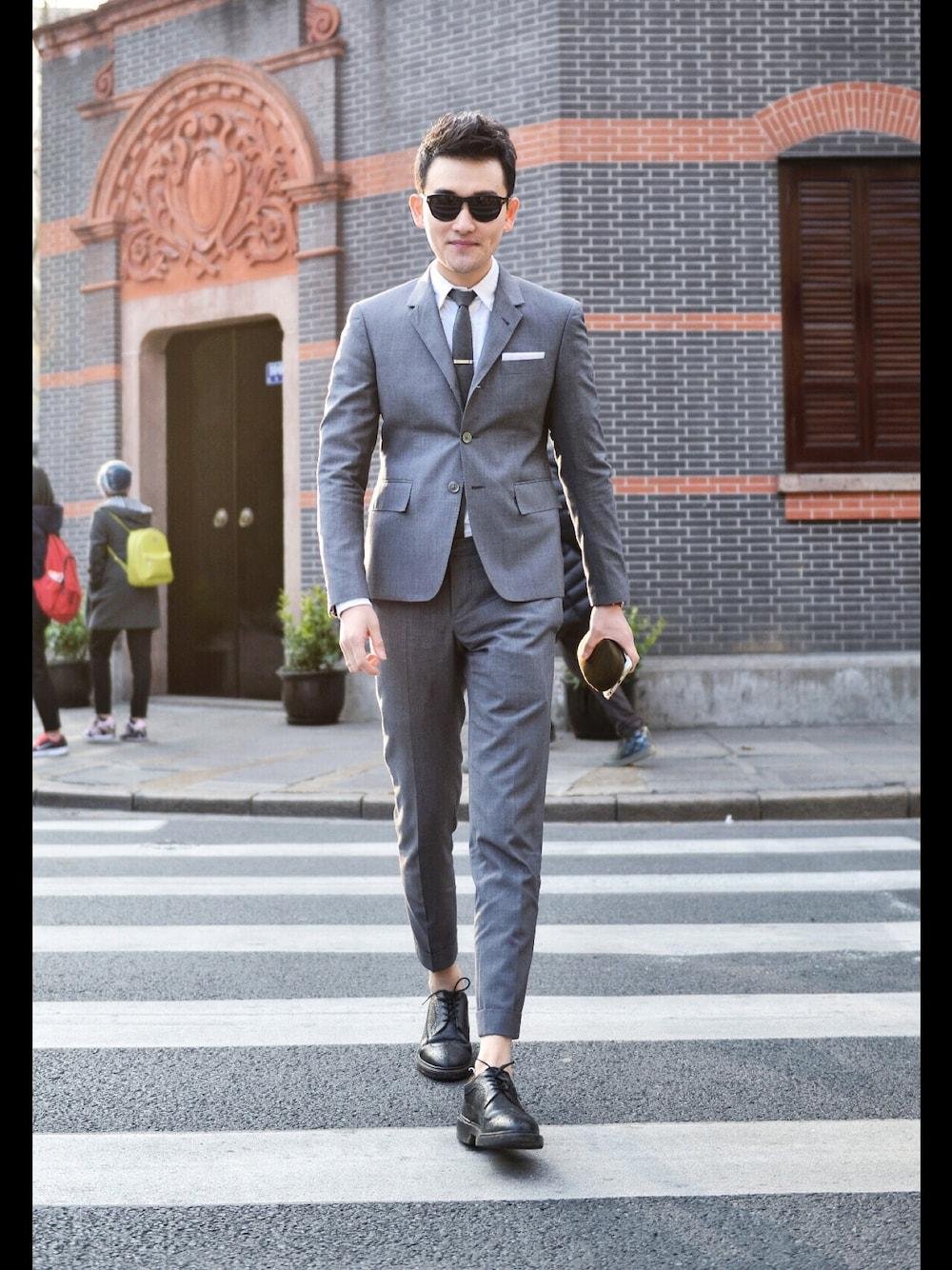 Model styling a Thom Browne suit with a white shirt, narrow tie and black shoes.