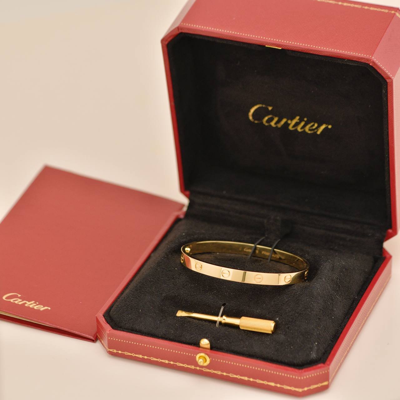 Yellow-gold Cartier Love Bracelet and screwdriver in a red Cartier presentation box.