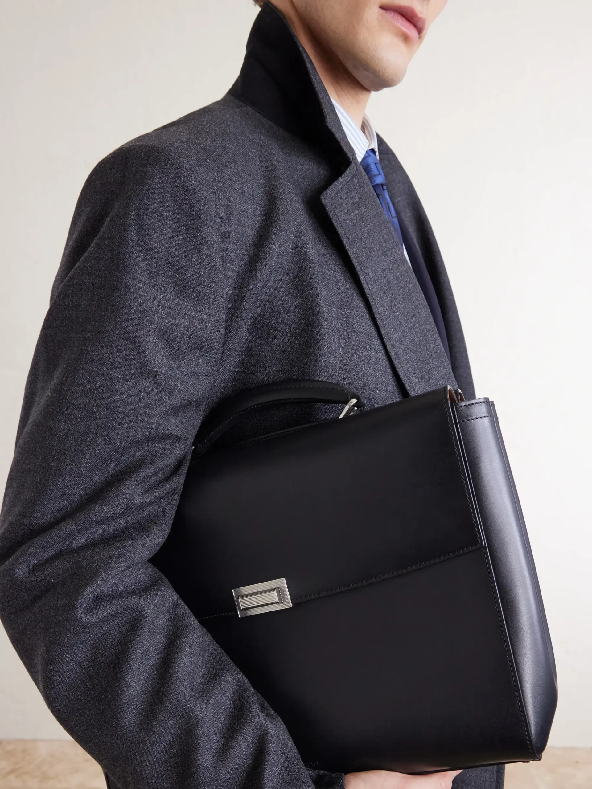 Model wearing a dark overcoat and carrying a black Dunhill Alfred 40 briefcase.