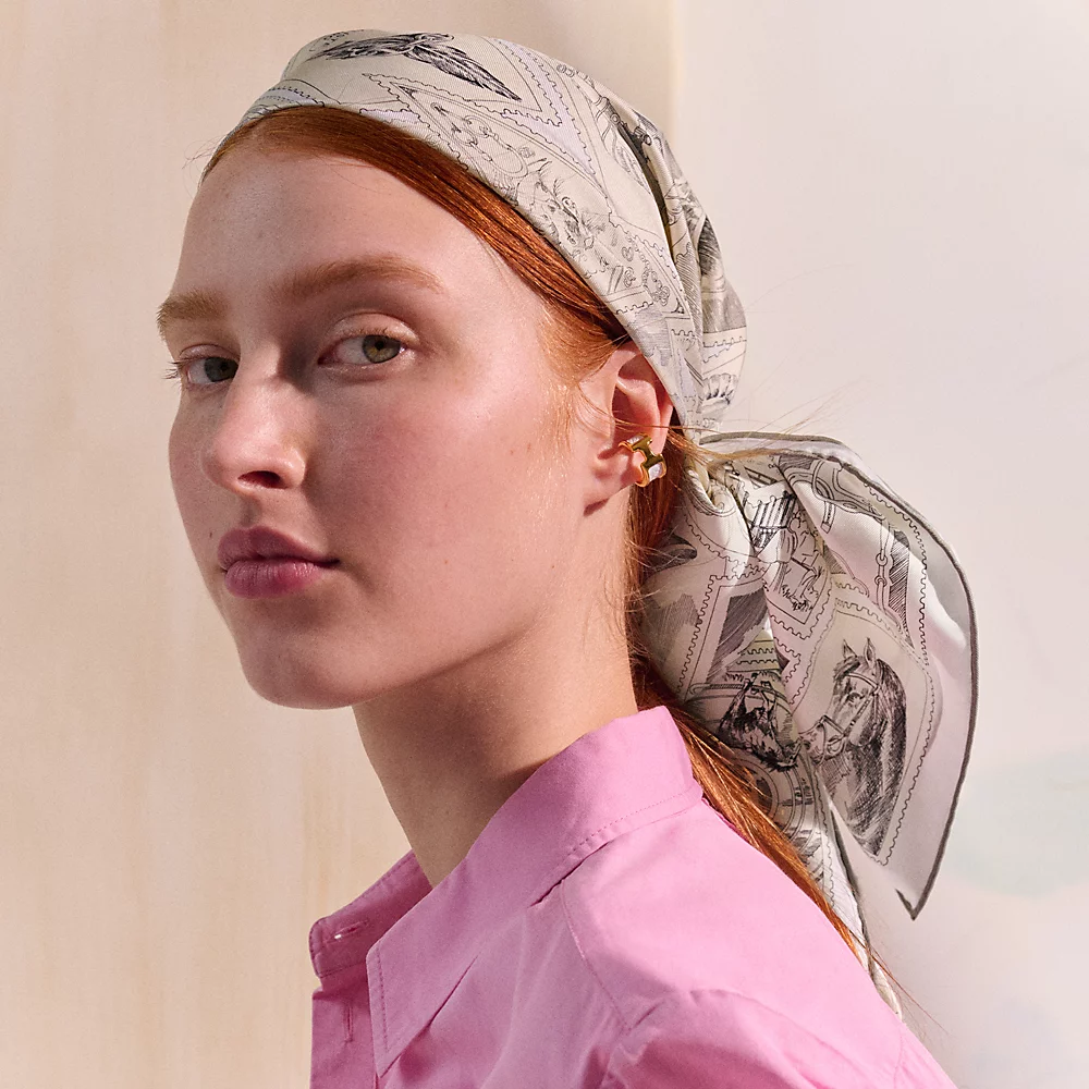 Model wearing a grey patterned Hermès Carré 90 as a headscarf.