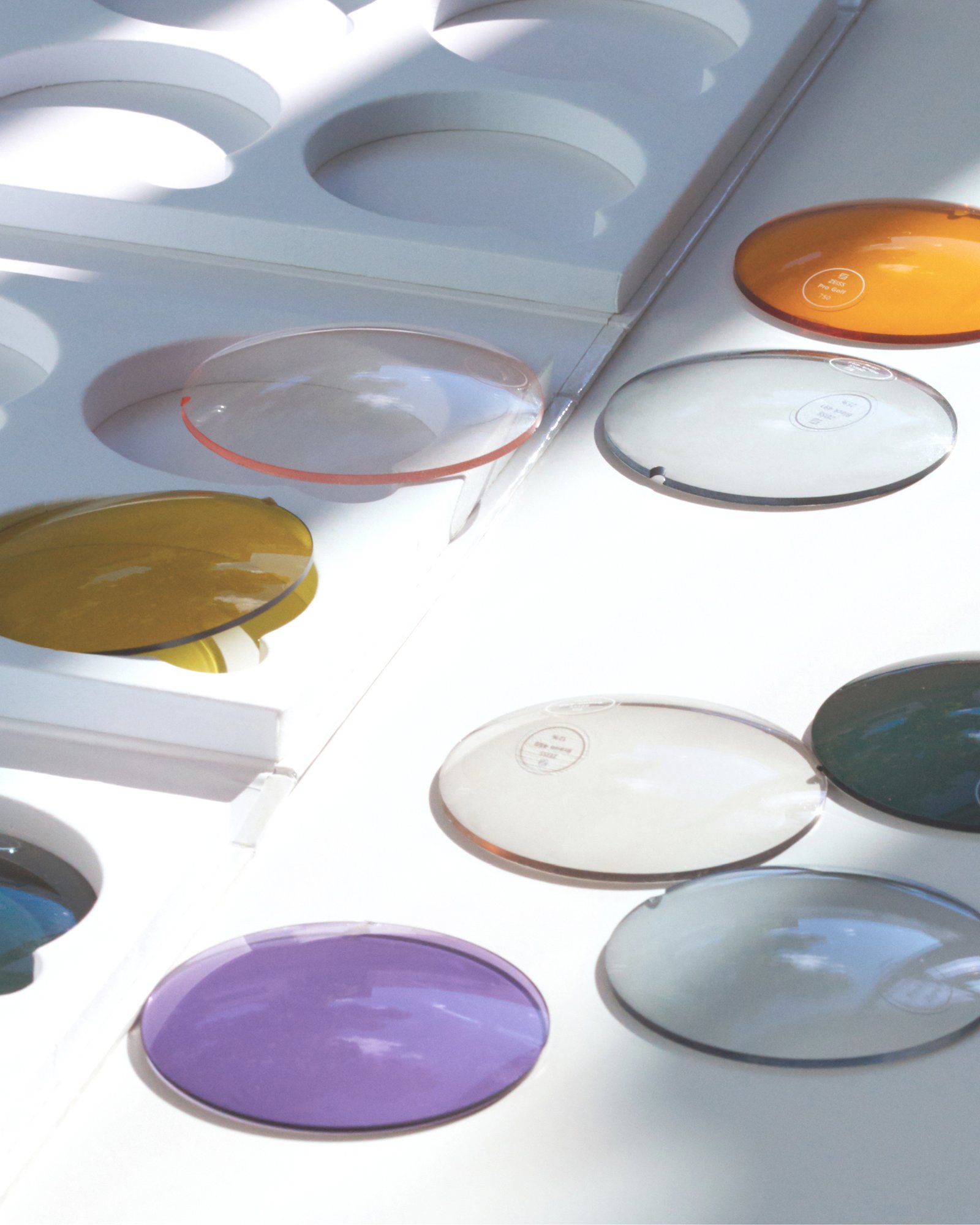 Clear and tinted MYKITA lenses arranged beside lens trays.
