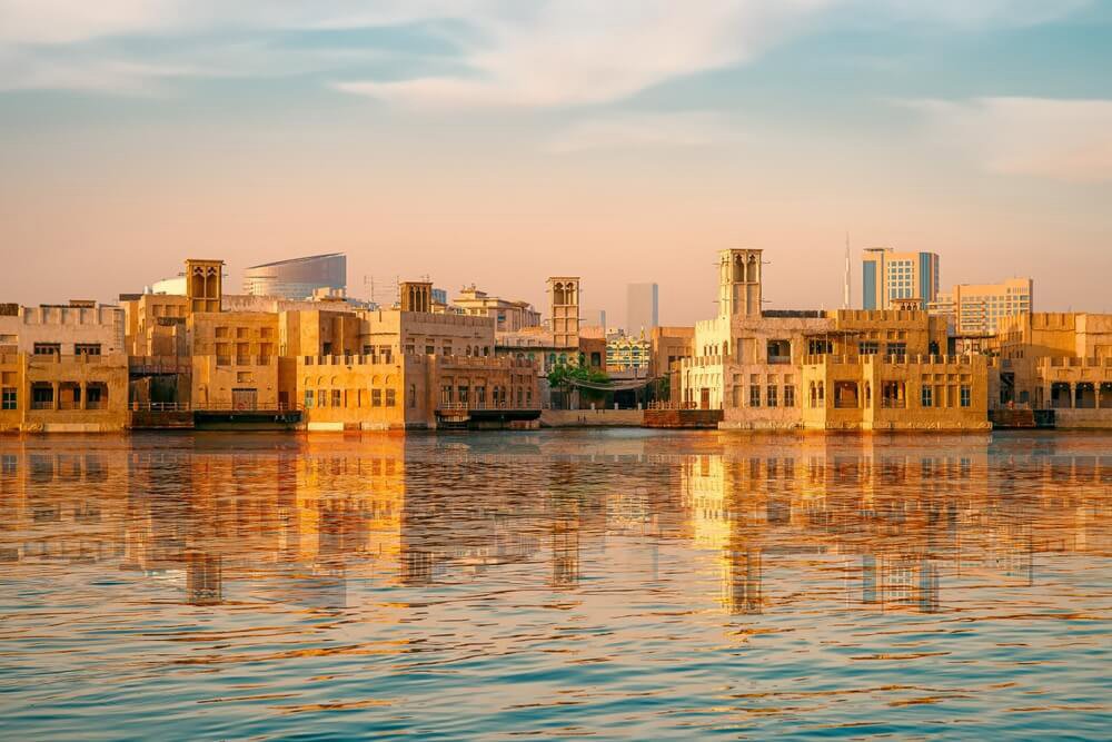 Waterfront buildings beside Dubai Creek in warm evening light