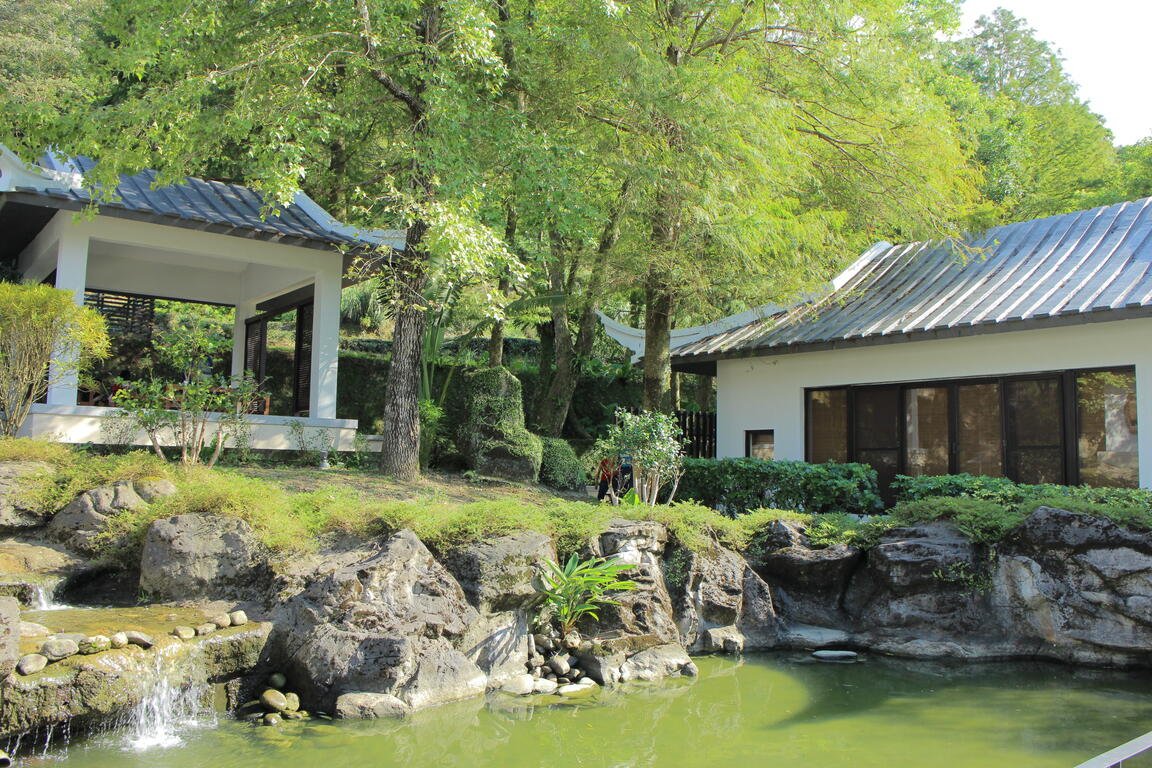 Pond, greenery and traditional-style buildings in the museum grounds