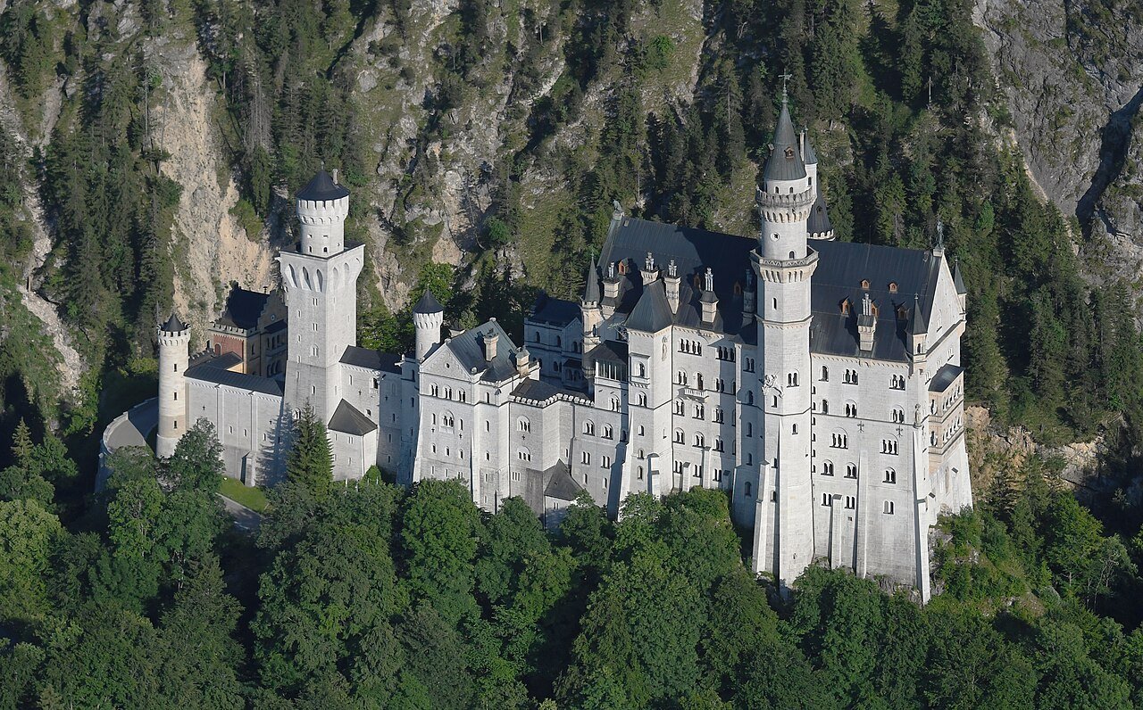 Aerial view of Neuschwanstein Castle beneath the Bavarian mountains.