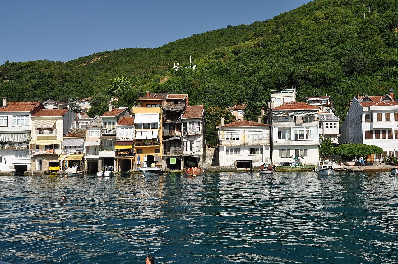 Anadolu Kavağı waterfront with boats, hillside buildings and restaurants.