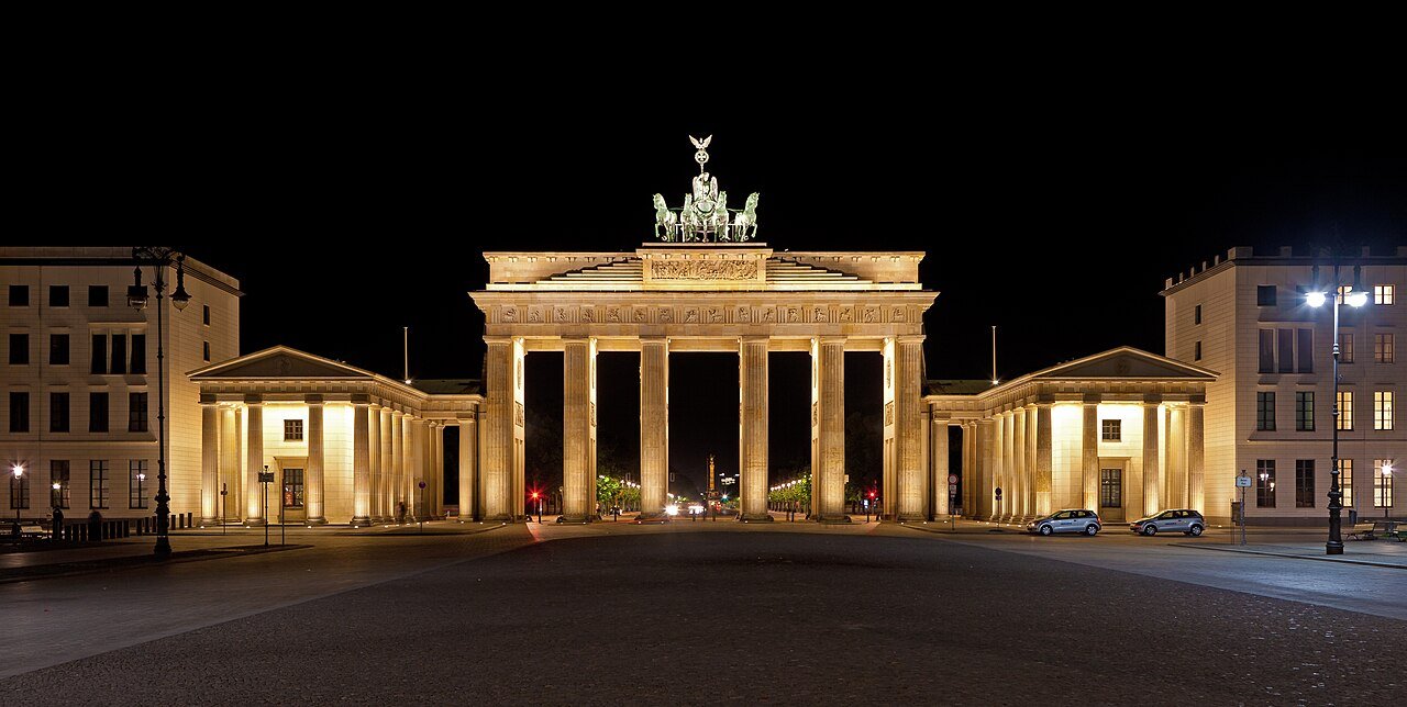 Front view of Brandenburg Gate illuminated after dark.
