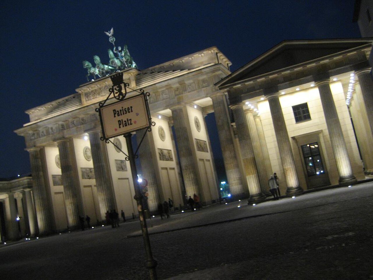 Angled night view of Brandenburg Gate and its illuminated passageways.