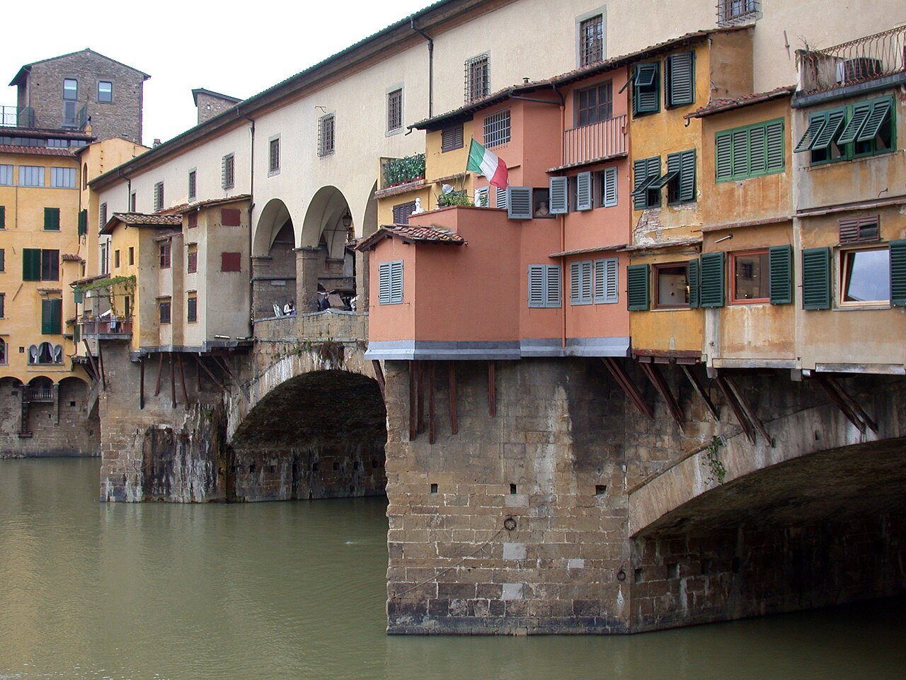 Projecting shops and wooden supports above a Ponte Vecchio stone arch.