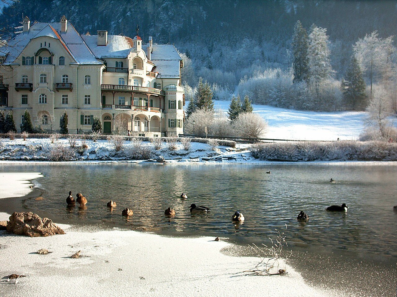 Snow-covered shore and buildings beside the Alpsee near Hohenschwangau.