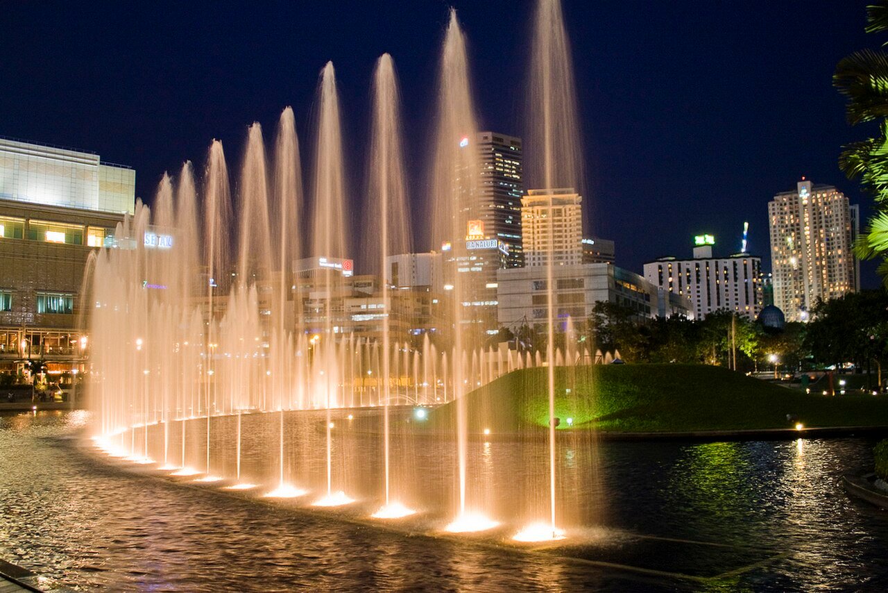 Illuminated Lake Symphony fountains in KLCC Park at night.