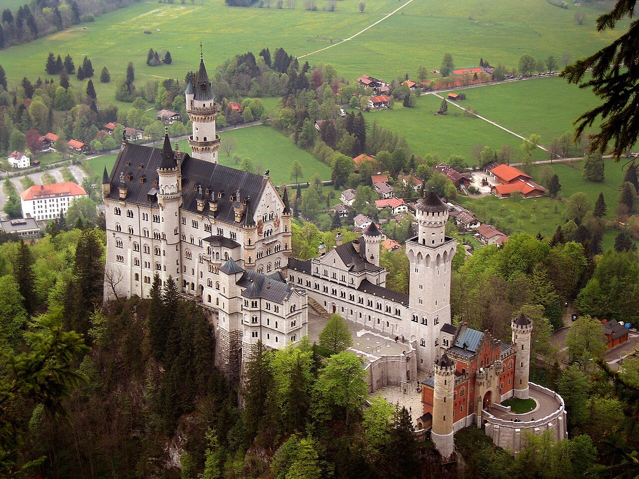 Neuschwanstein Castle and its wooded hillside above the countryside.
