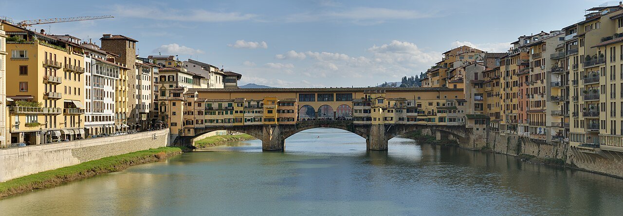 Panoramic riverbank view of Ponte Vecchio and its three stone arches.