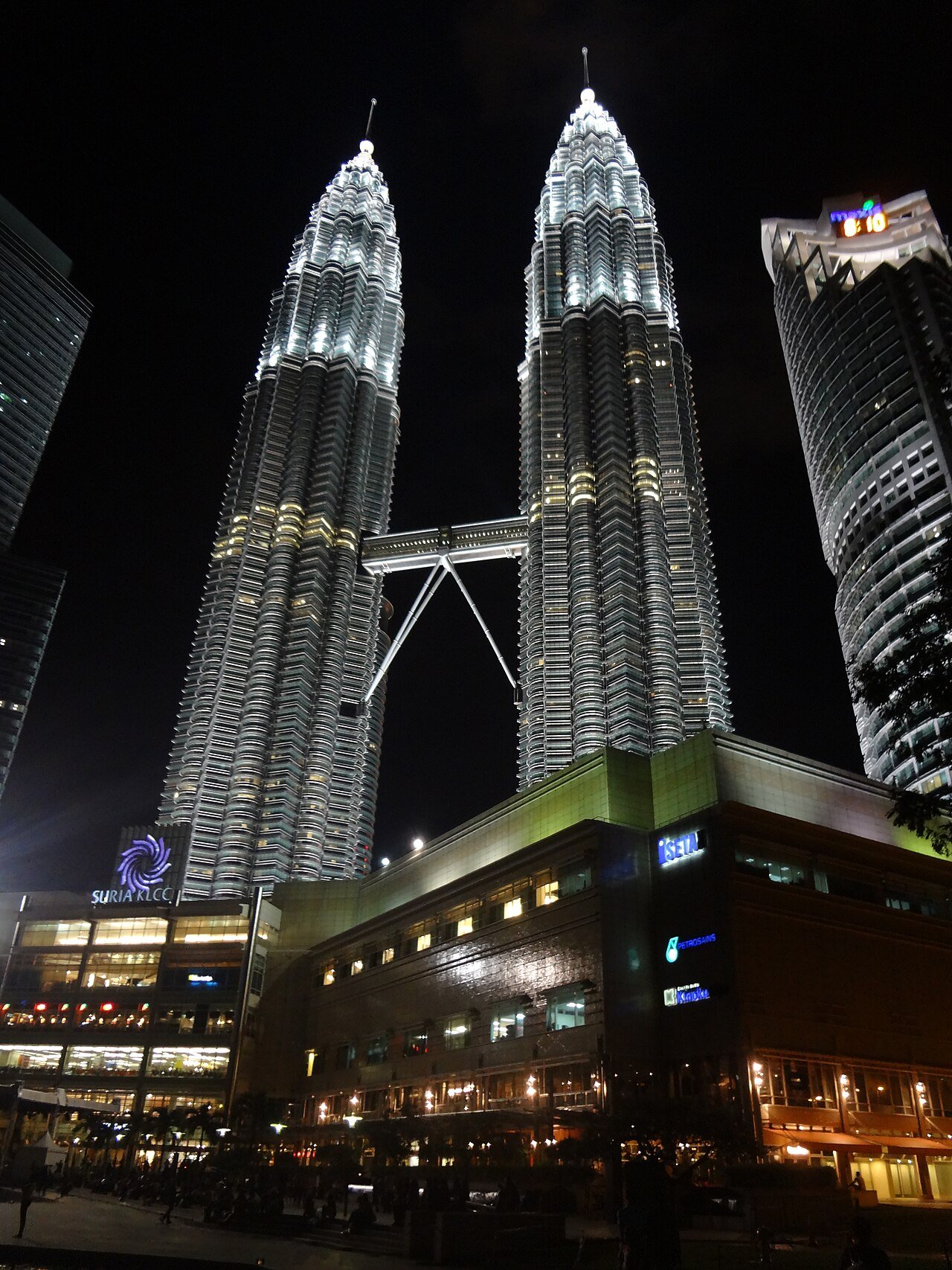 Petronas Twin Towers illuminated at night from ground level.