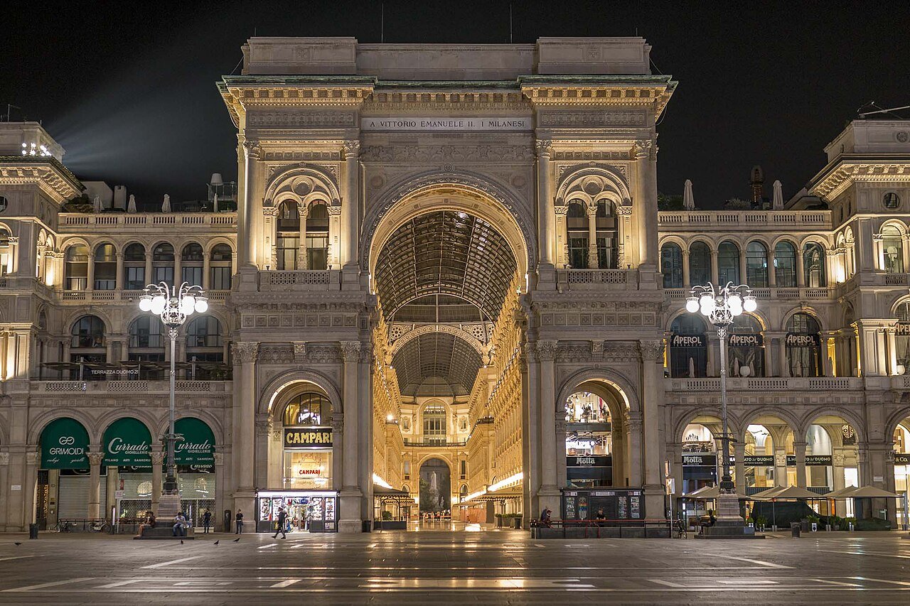 Illuminated Galleria entrance seen from Piazza del Duomo at night.