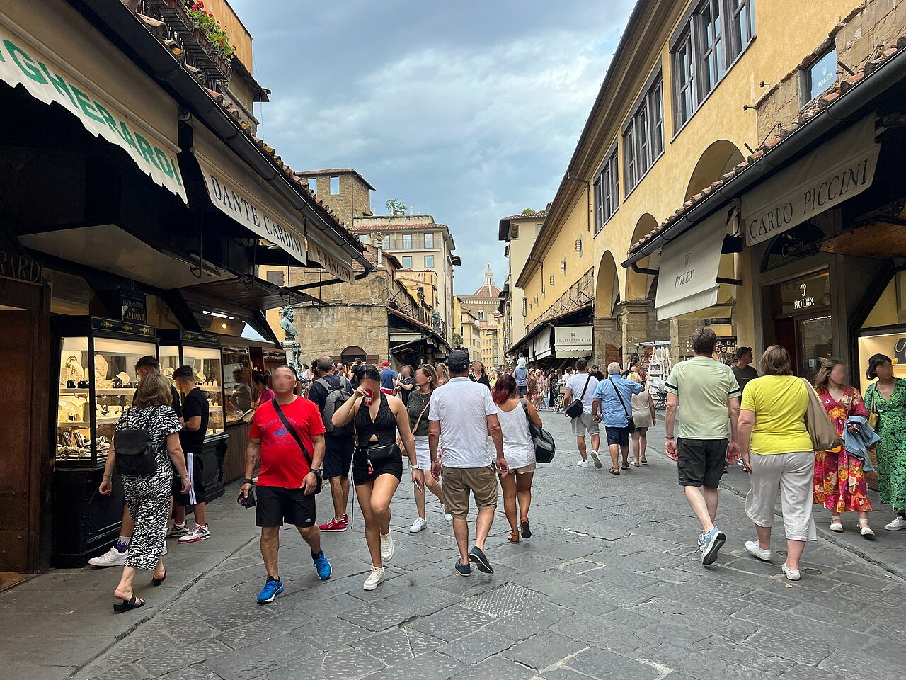 Visitors walking between shopfronts on Ponte Vecchio.