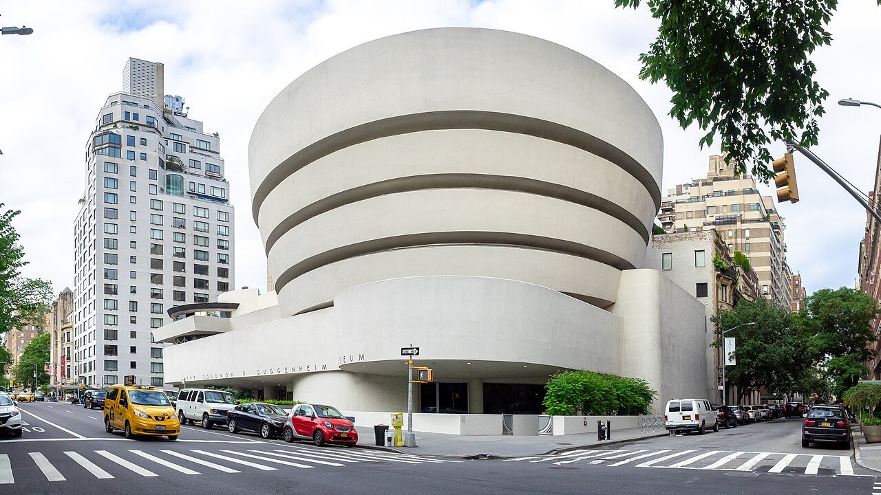 Guggenheim Museum exterior with traffic and pedestrians.