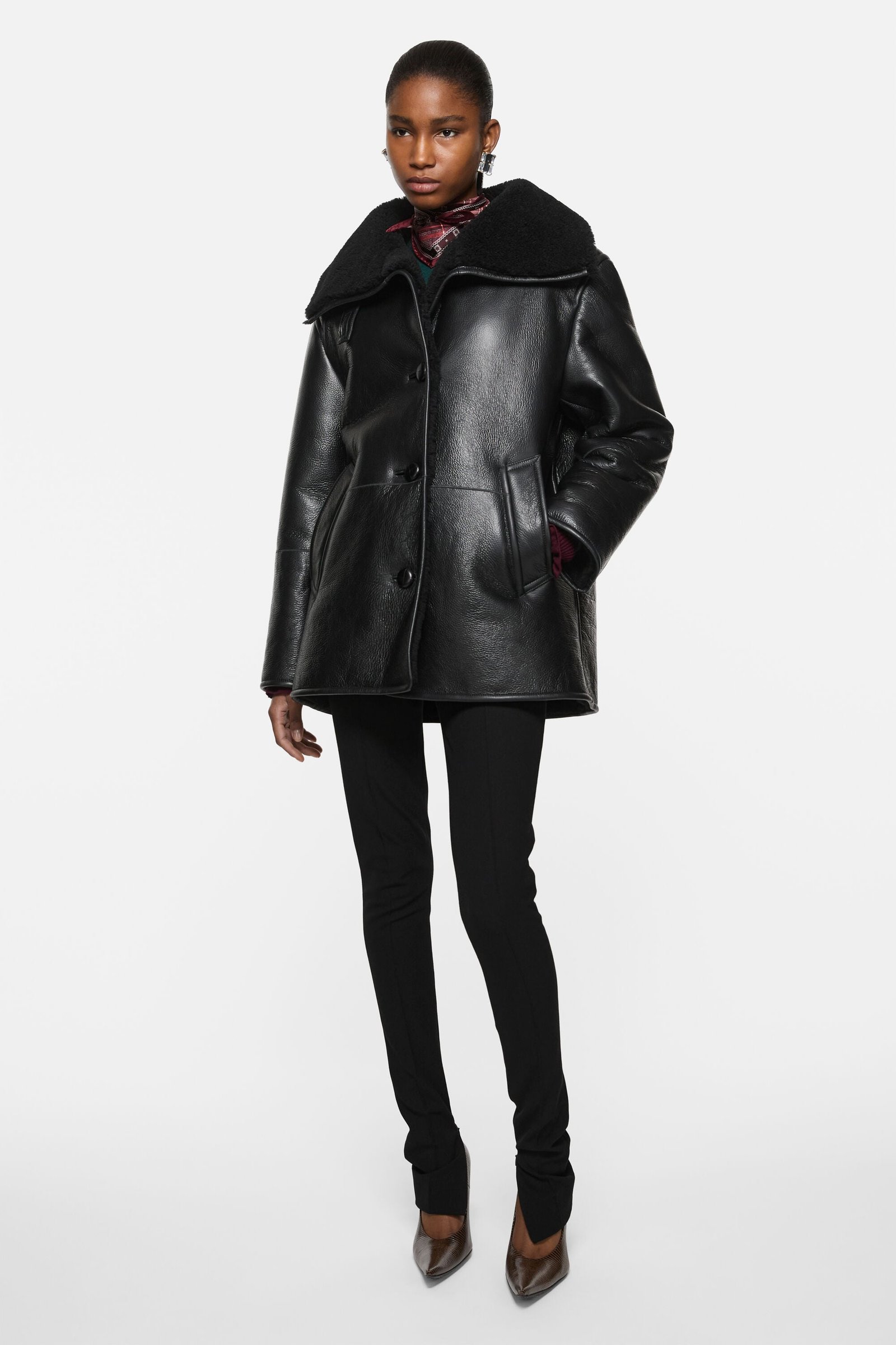 Model wearing a leather shearling duffle coat with winter layers.