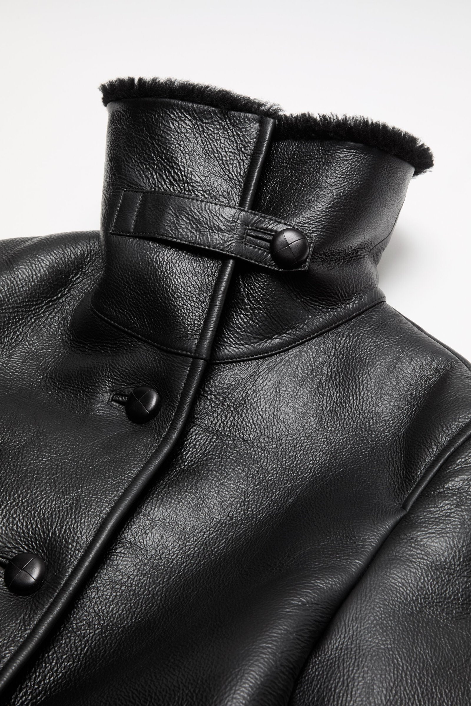 Close view of a shearling coat collar and neck tab.