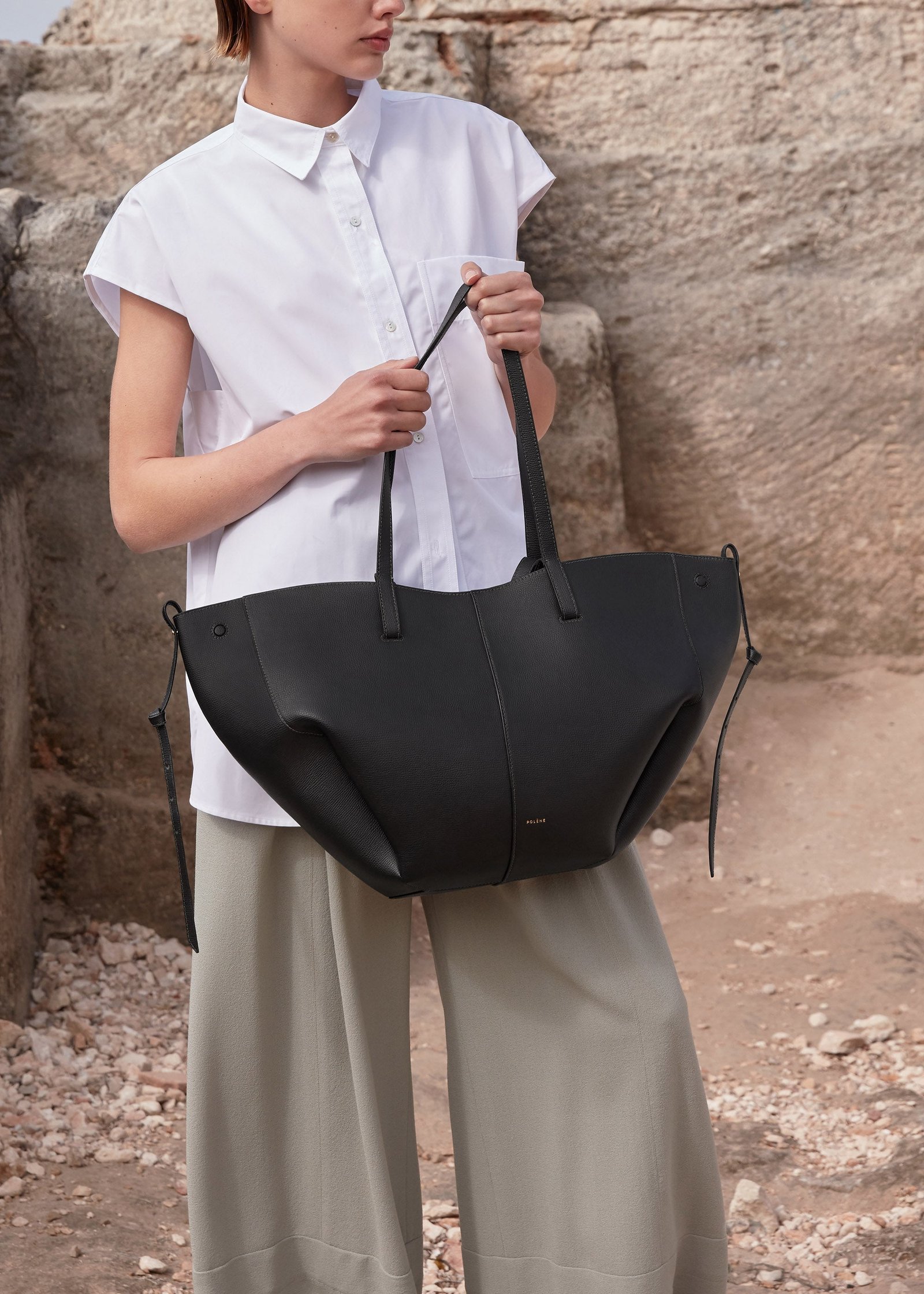 Model holding a black Polène Cyme with its sides extended