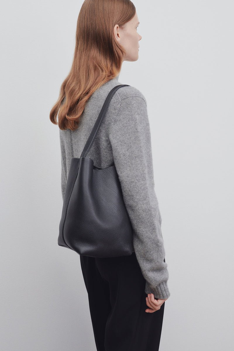 Model wearing The Row medium N/S Park Tote with tailored clothing.
