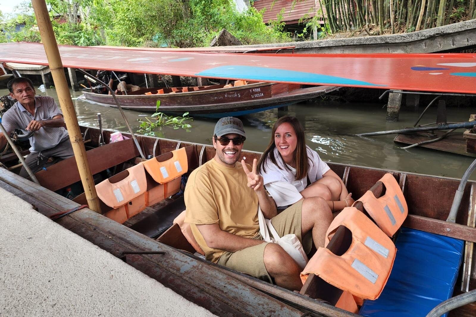 Visitors sitting in a wooden boat with life jackets.
