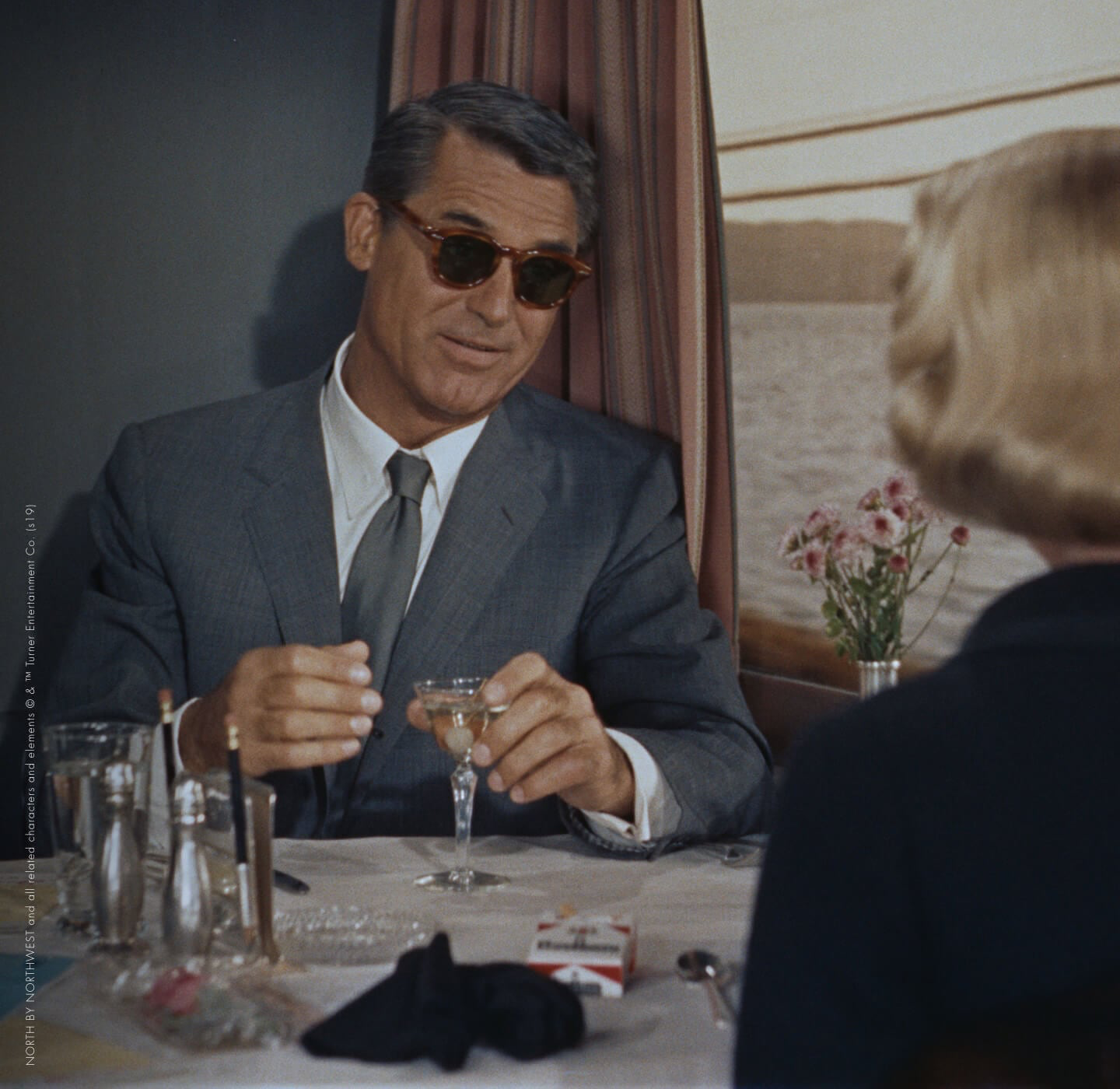 Man wearing Oliver Peoples sunglasses with a dark tailored suit