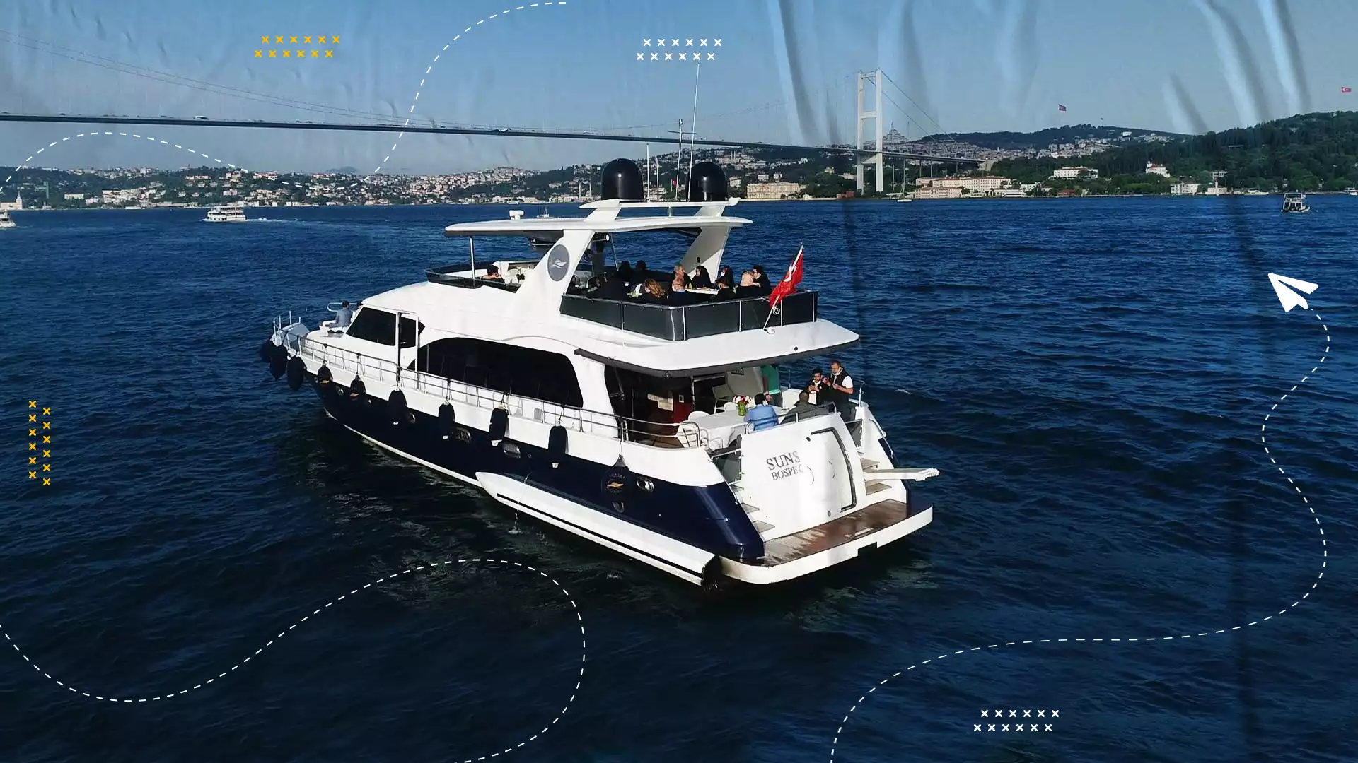 Sightseeing yacht cruising the Bosphorus with a suspension bridge in the background.