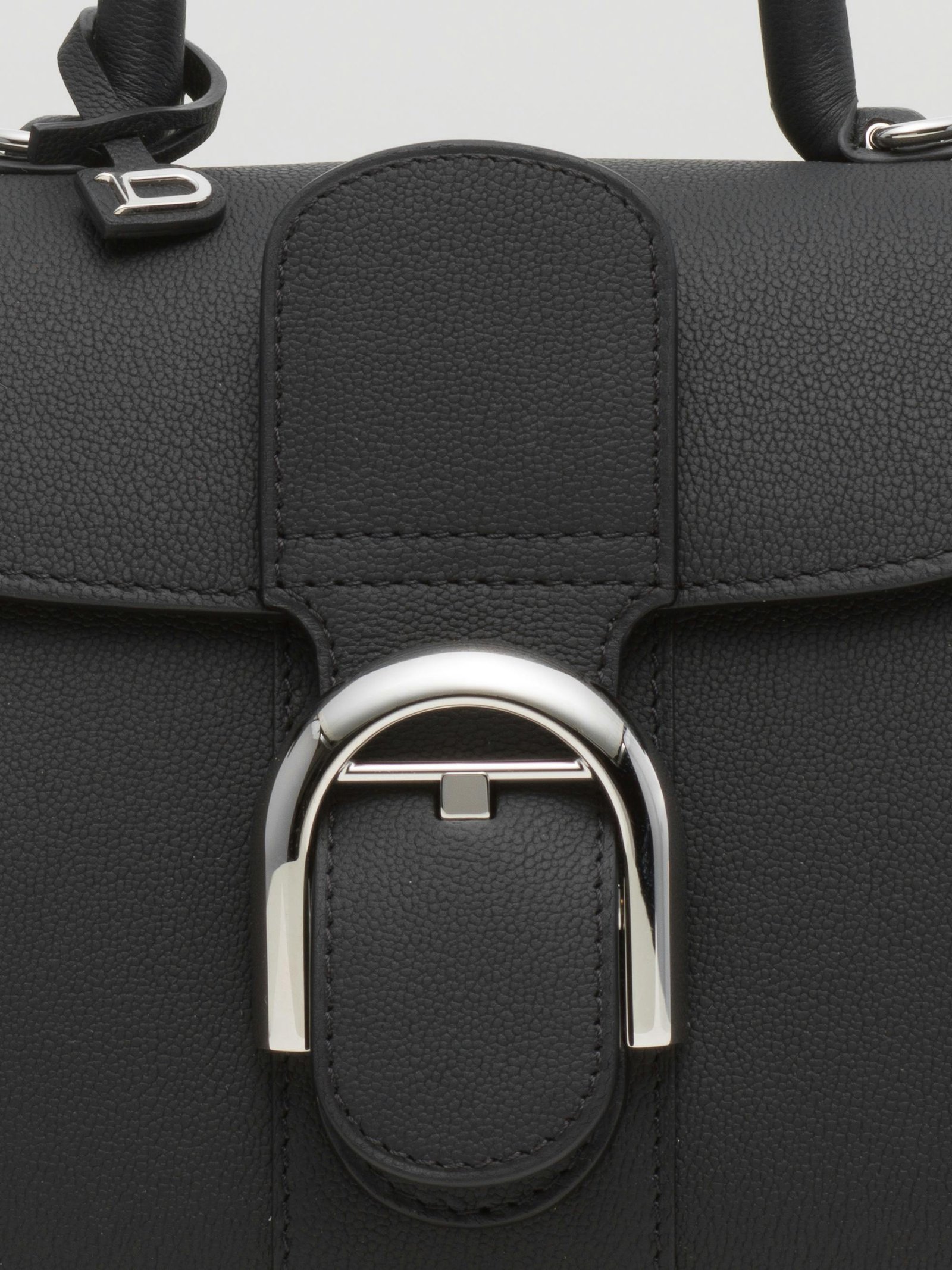 Close-up of the curved Brillant buckle and grained black leather.