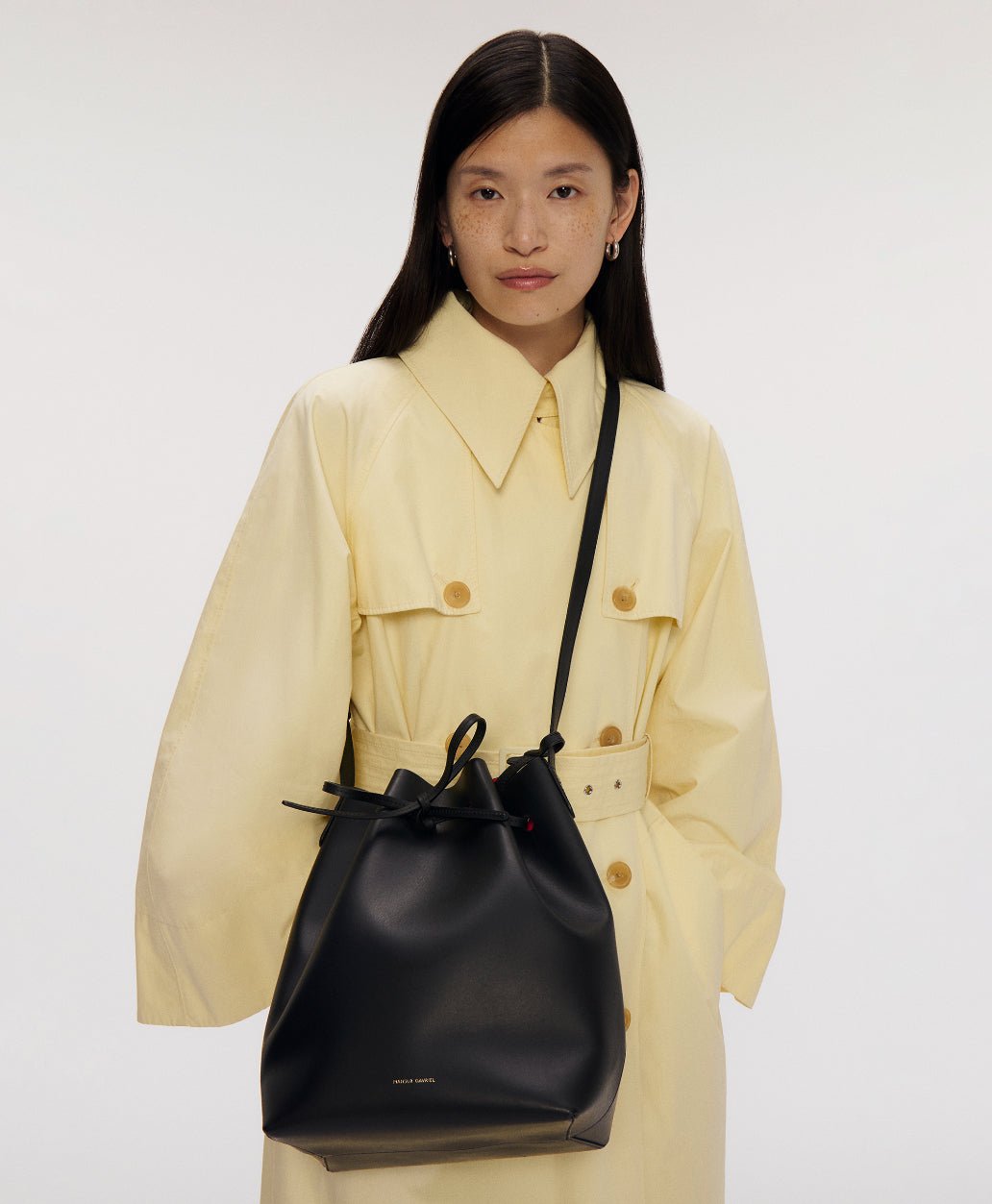 Model wearing a black Mansur Gavriel Bucket Bag with a yellow shirt