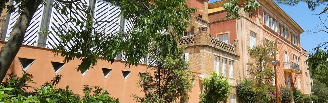 Exterior of the pink Gaudí House Museum among the park gardens.