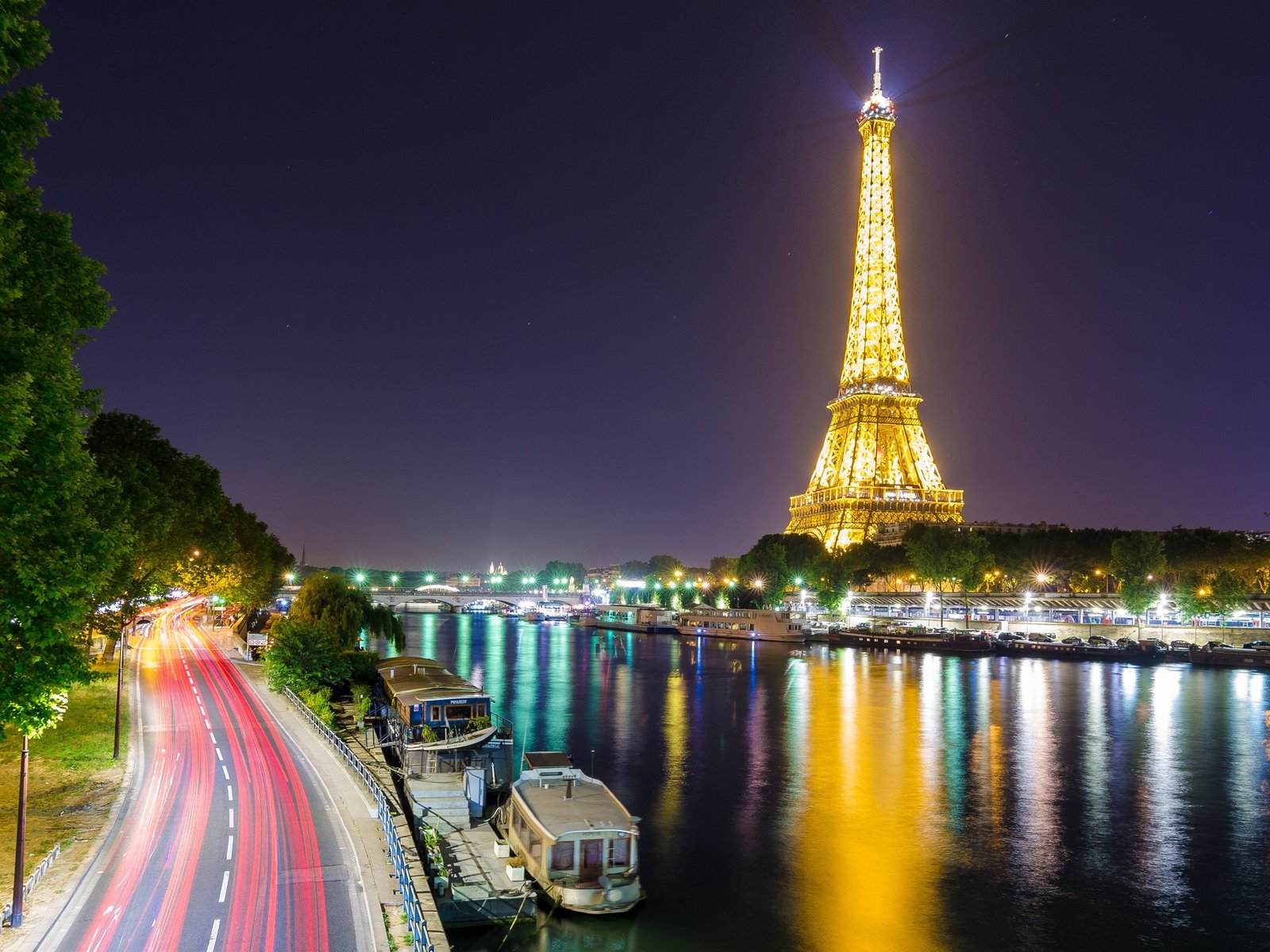 Eiffel Tower illuminated above the Seine.