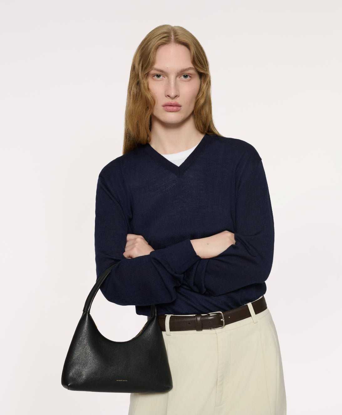 Model carrying a black Mini Candy Bag with a navy knit and light trousers