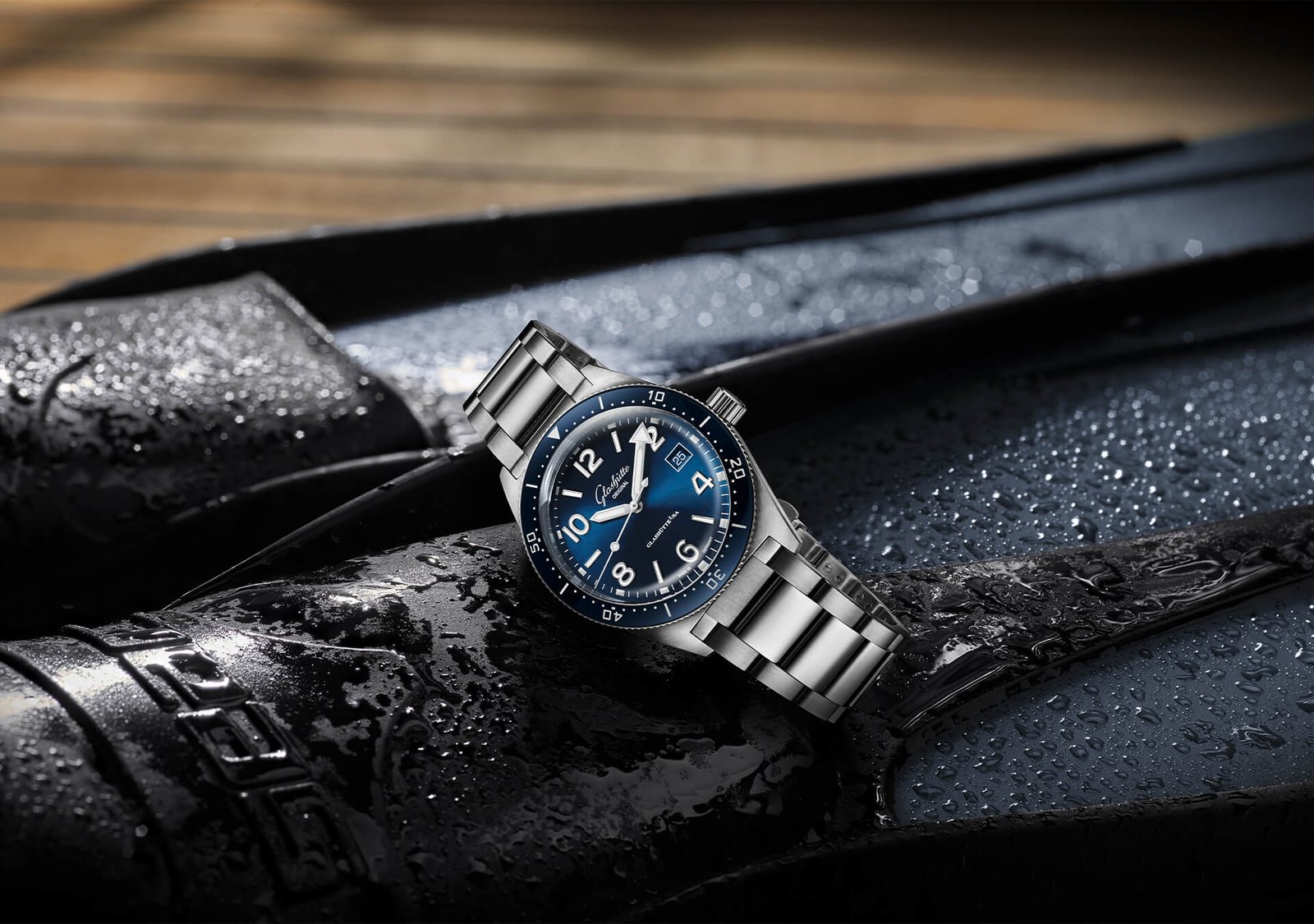 Blue Glashütte Original SeaQ with a steel bracelet beside diving equipment.
