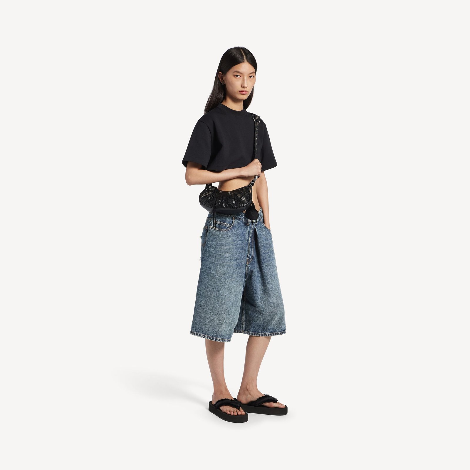 Model carrying the black Le Cagole XS with a simple tee and denim skirt.