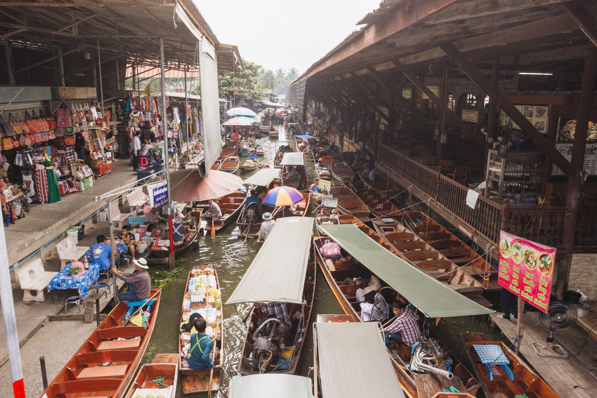 Overview of boats and canal-side stalls at Damnoen Saduak.