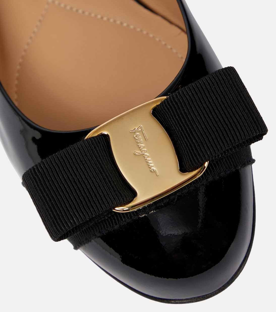 Rounded toe and grosgrain bow on a black patent-leather ballet flat.