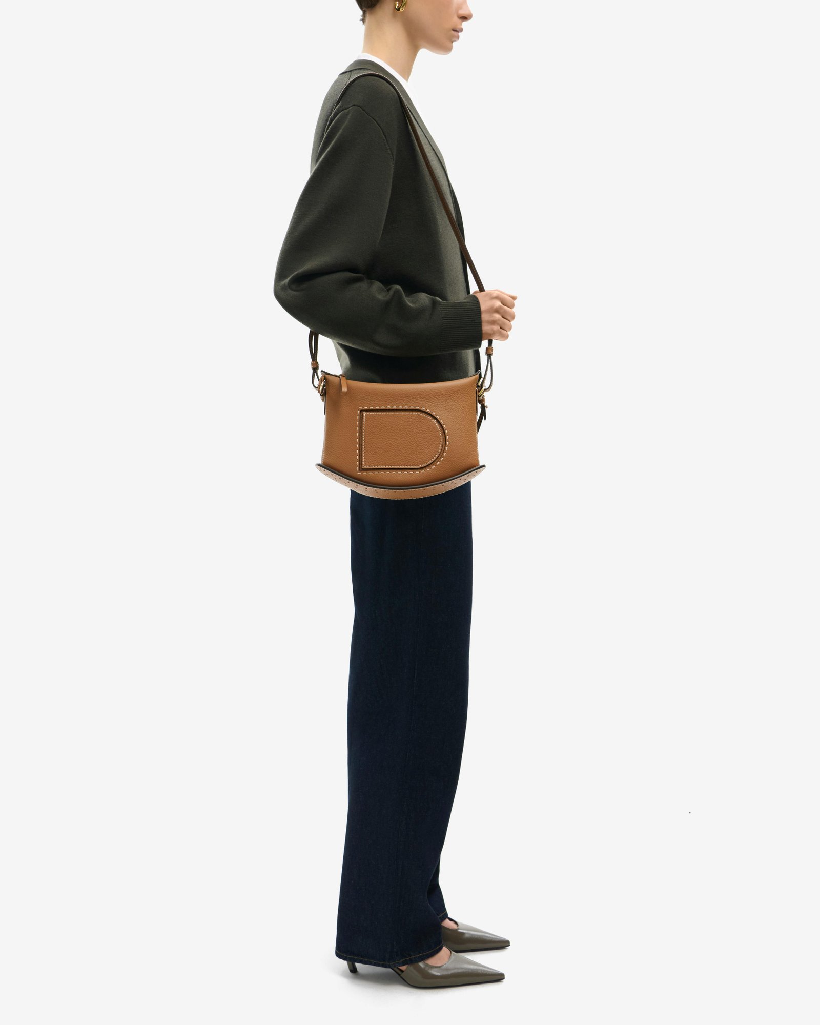 Model wearing a tan Delvaux Pin Swing with a shoulder strap.
