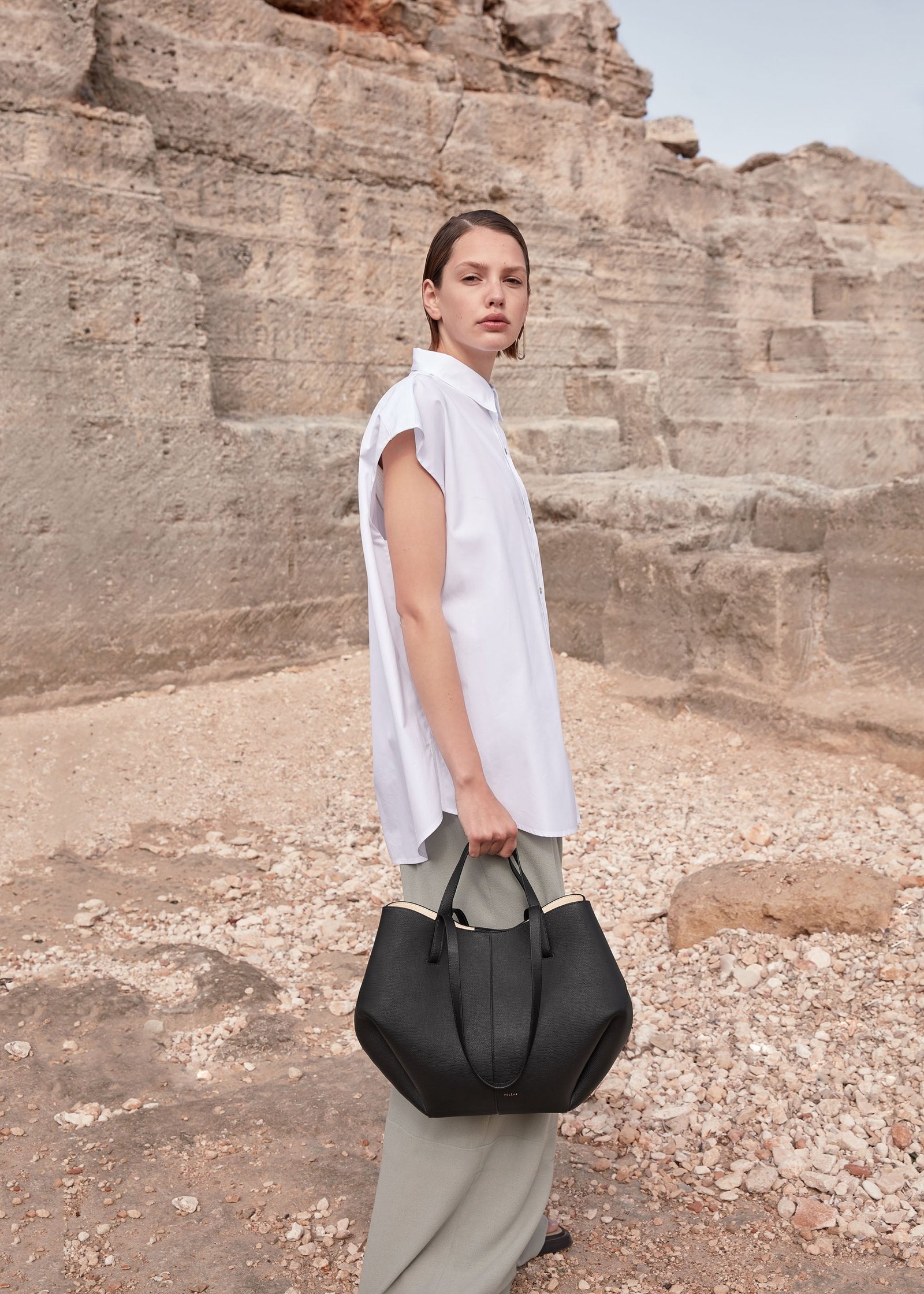 Model carrying a black Polène Cyme with its sides folded inward