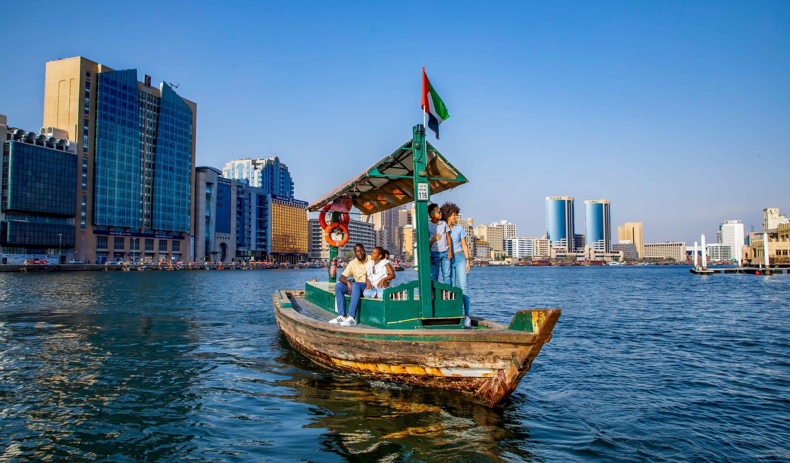 Traditional abra crossing Dubai Creek beside the waterfront buildings