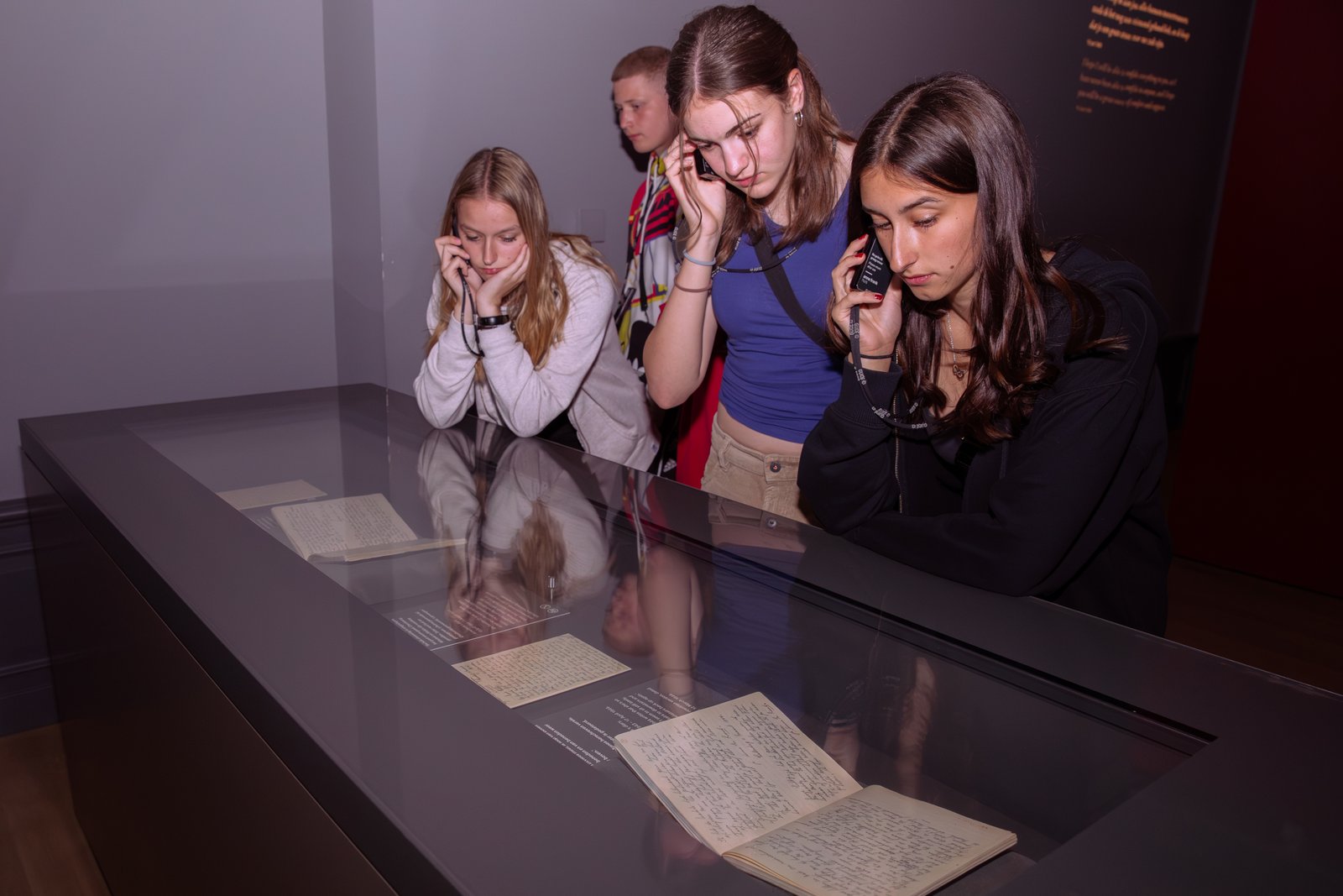 Museum visitors wearing audio headsets beside a display.