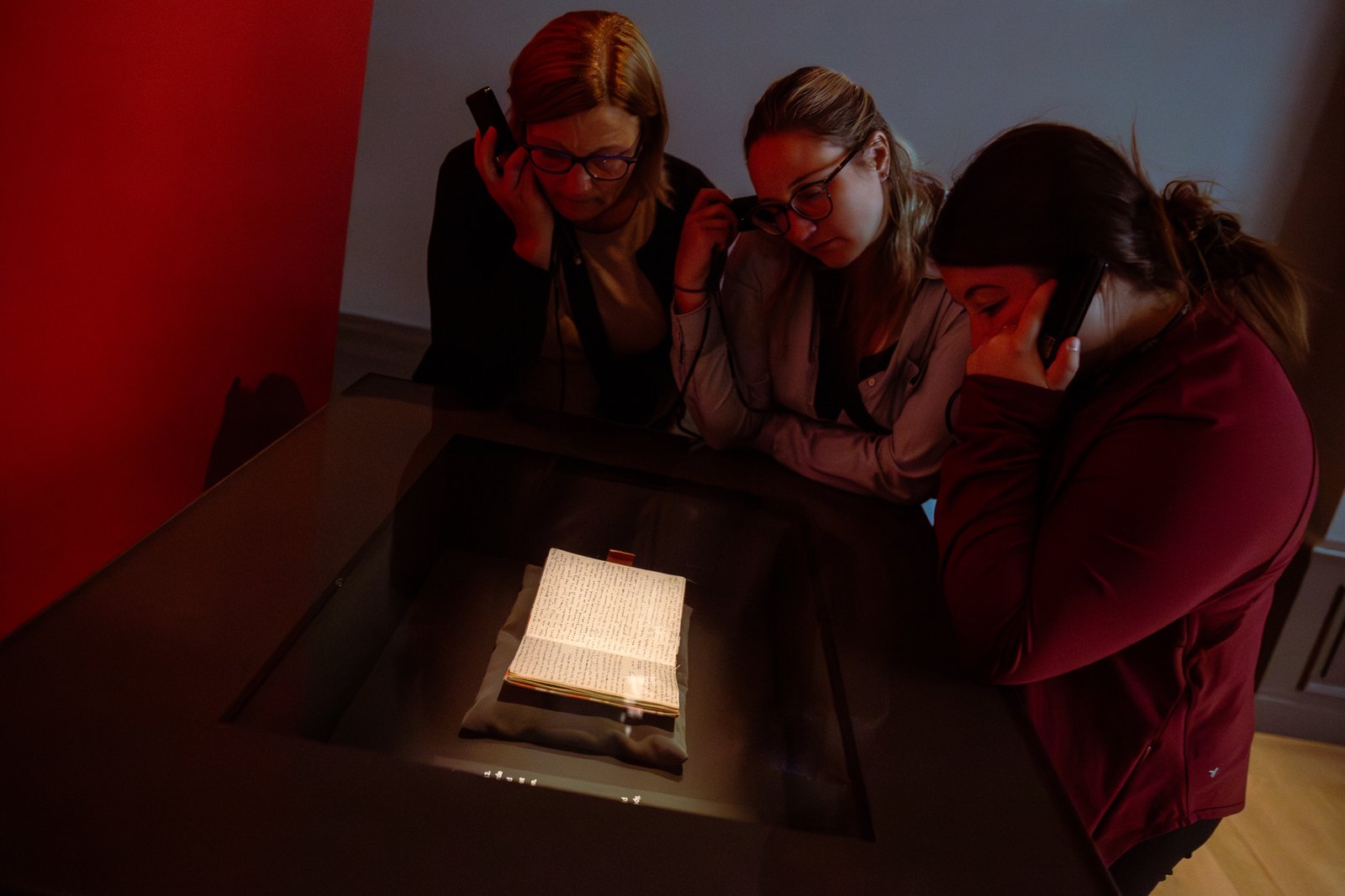 Museum visitors gathered around an illuminated writing display.