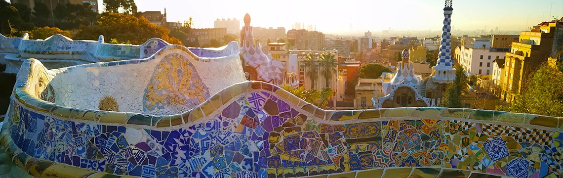 Warm evening light over the mosaic bench and Barcelona skyline.