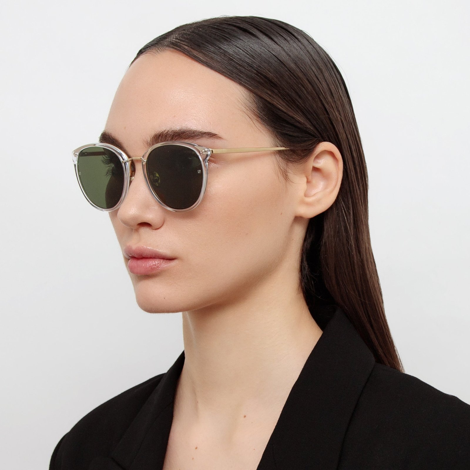Model wearing clear Linda Farrow Calthorpe sunglasses with a black blazer.
