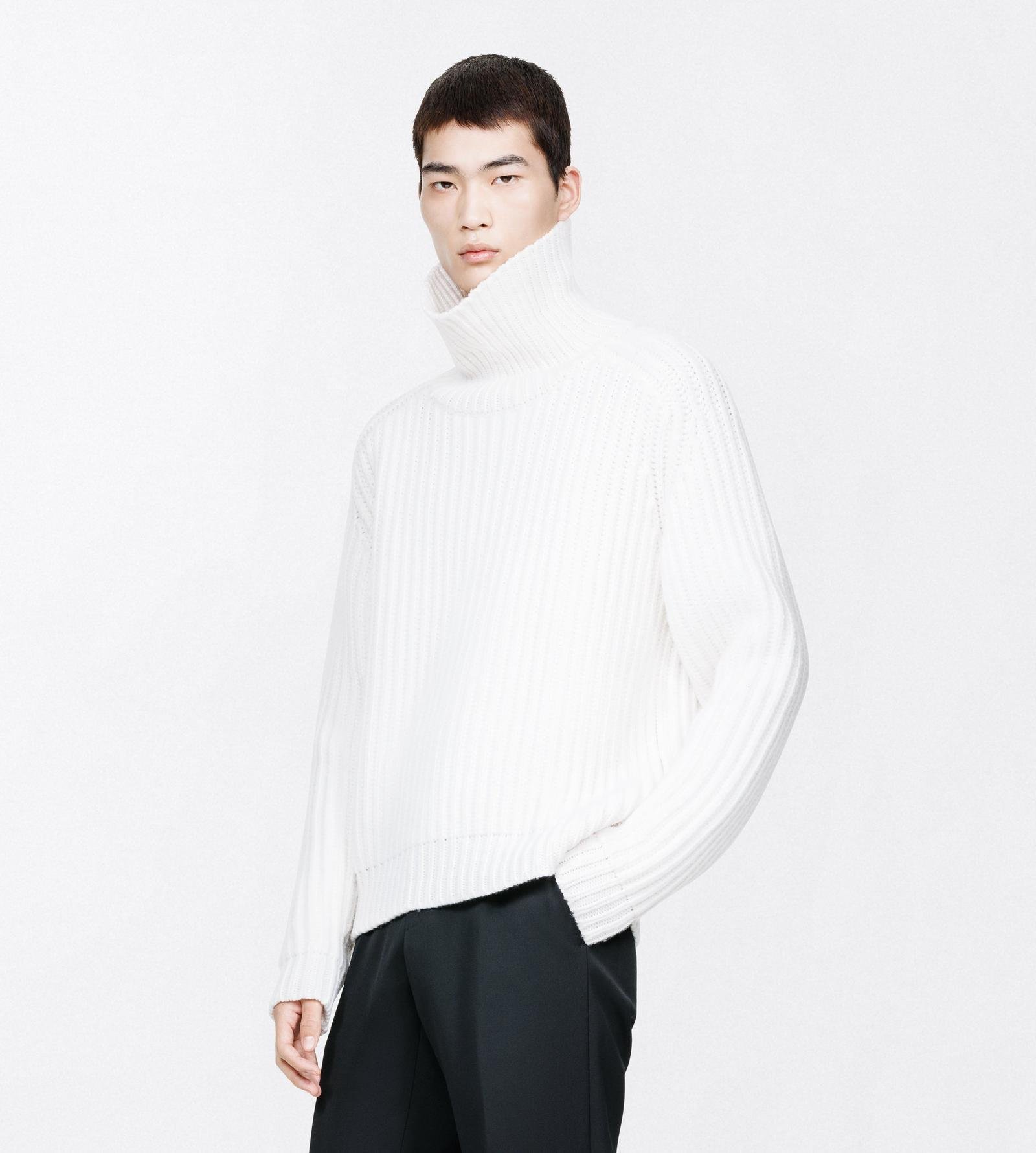 Man wearing an ivory ribbed cashmere roll-neck with dark trousers